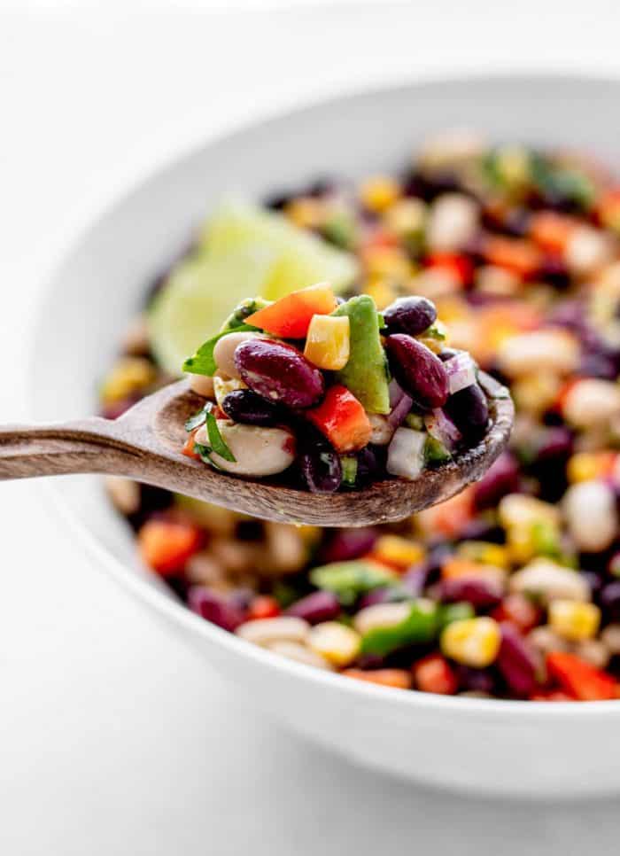 Mixed bean salad on a wooden spoon.