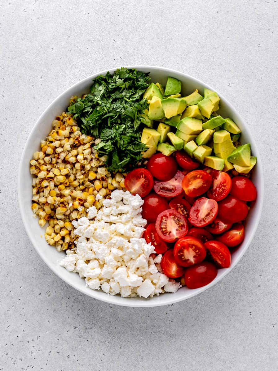 The ingredients for grilled corn salad in a white bowl.