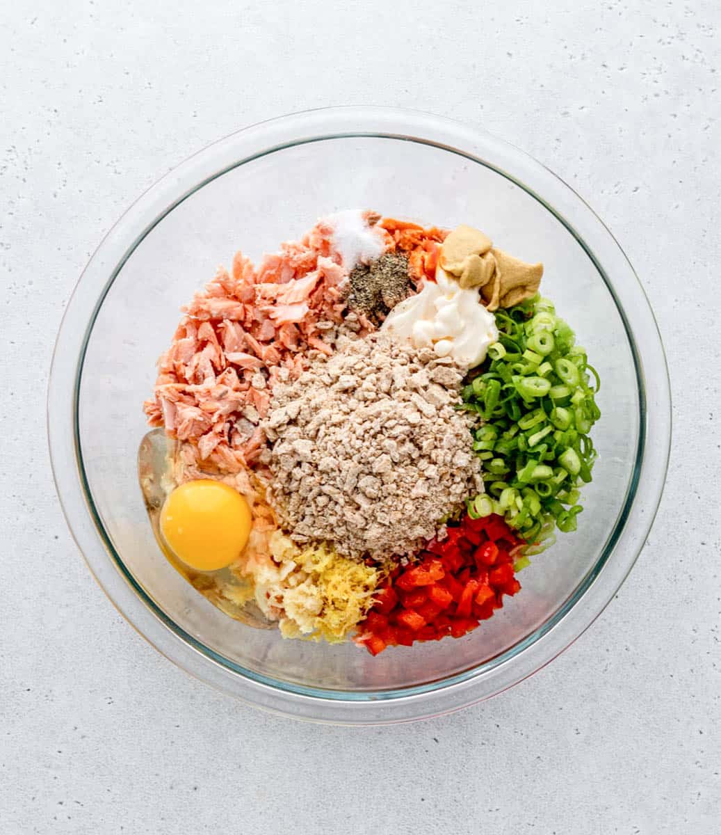 Bell pepper, green onions, egg, whole-wheat cracker crumbs, salmon, seasonings, Dijon, Worcestershire, and mayo in a glass bowl.