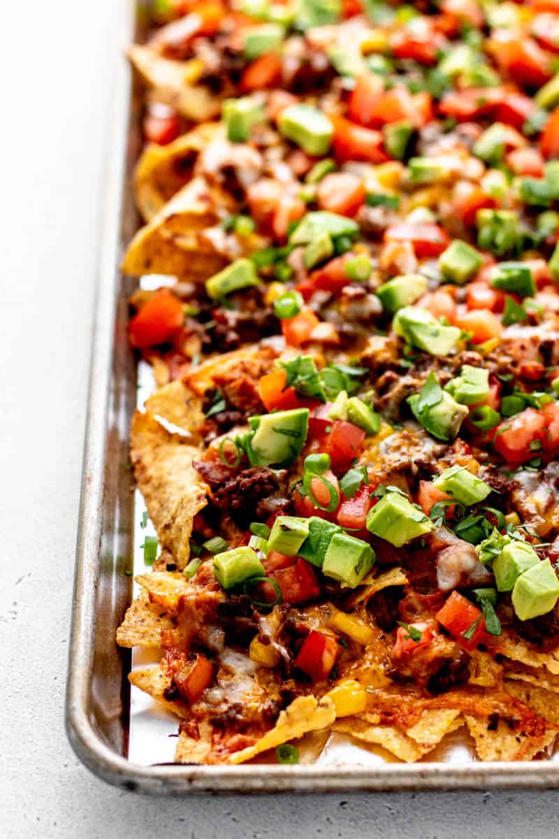 A pan of beef supreme nachos with tomatoes, avocado and fresh cilantro.