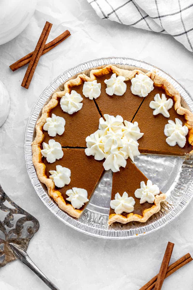 Overhead image of a baked easy pumpkin pie topped with dollops of whipped cream.