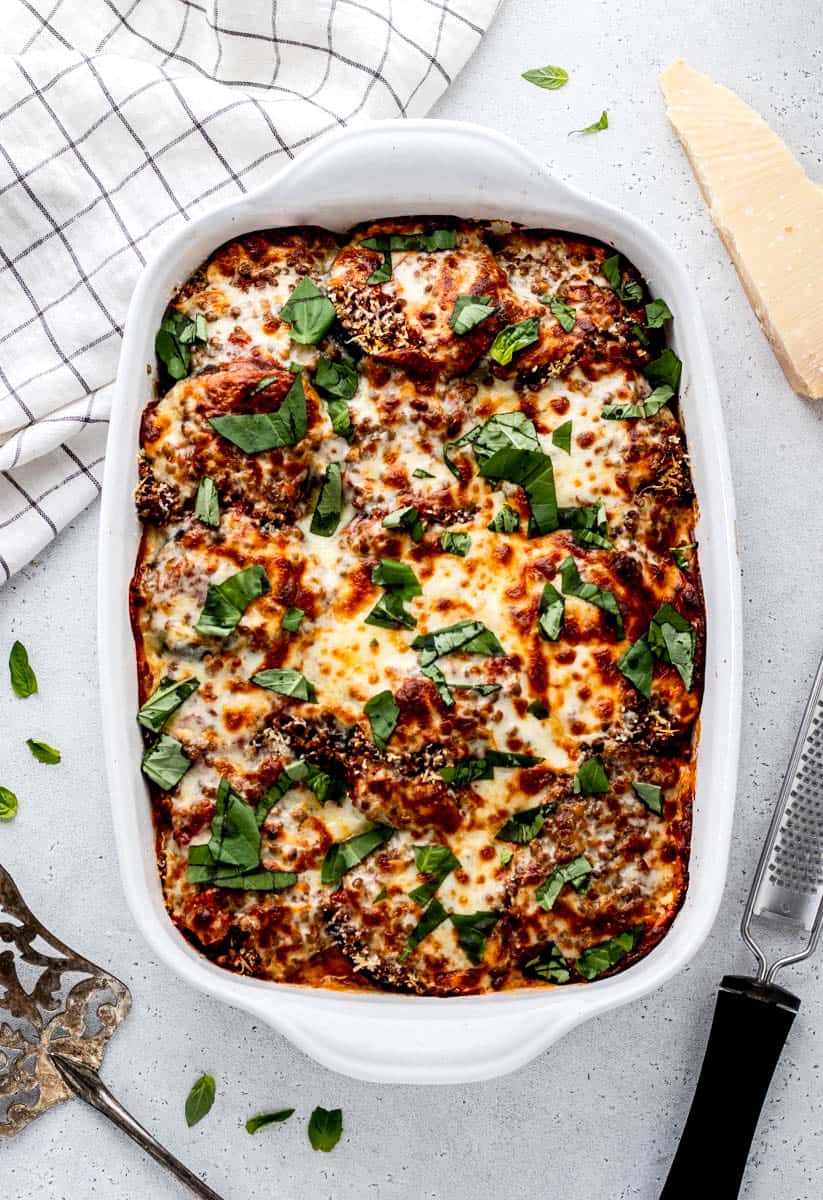 Baked eggplant parmesan in a white baking dish topped with fresh herbs.
