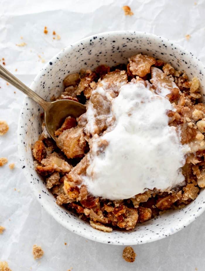 A spoon digging into a bowl of almond flour apple crisp.
