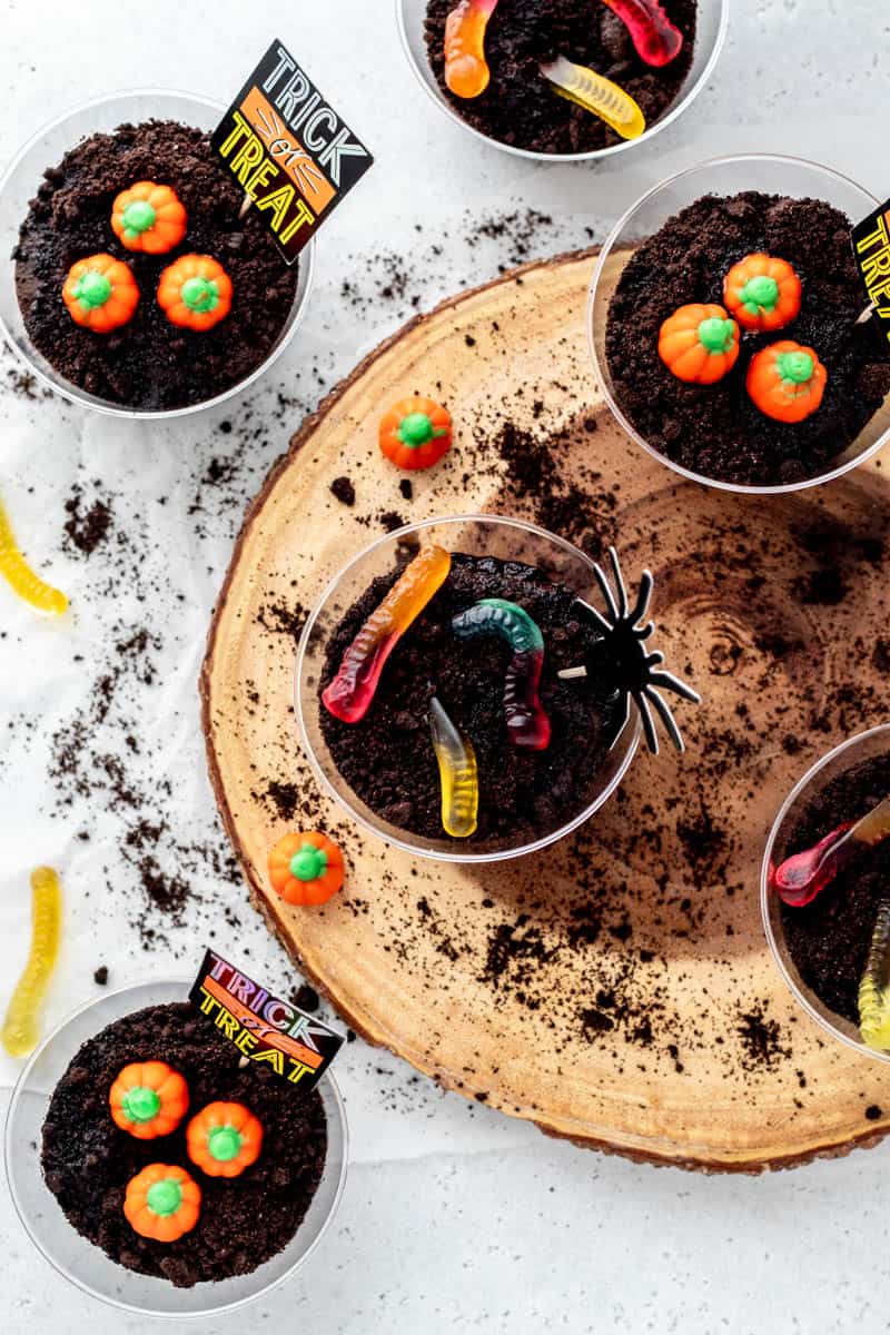 Overhead image of dirt pudding cups with gummy worms and pumpkins.
