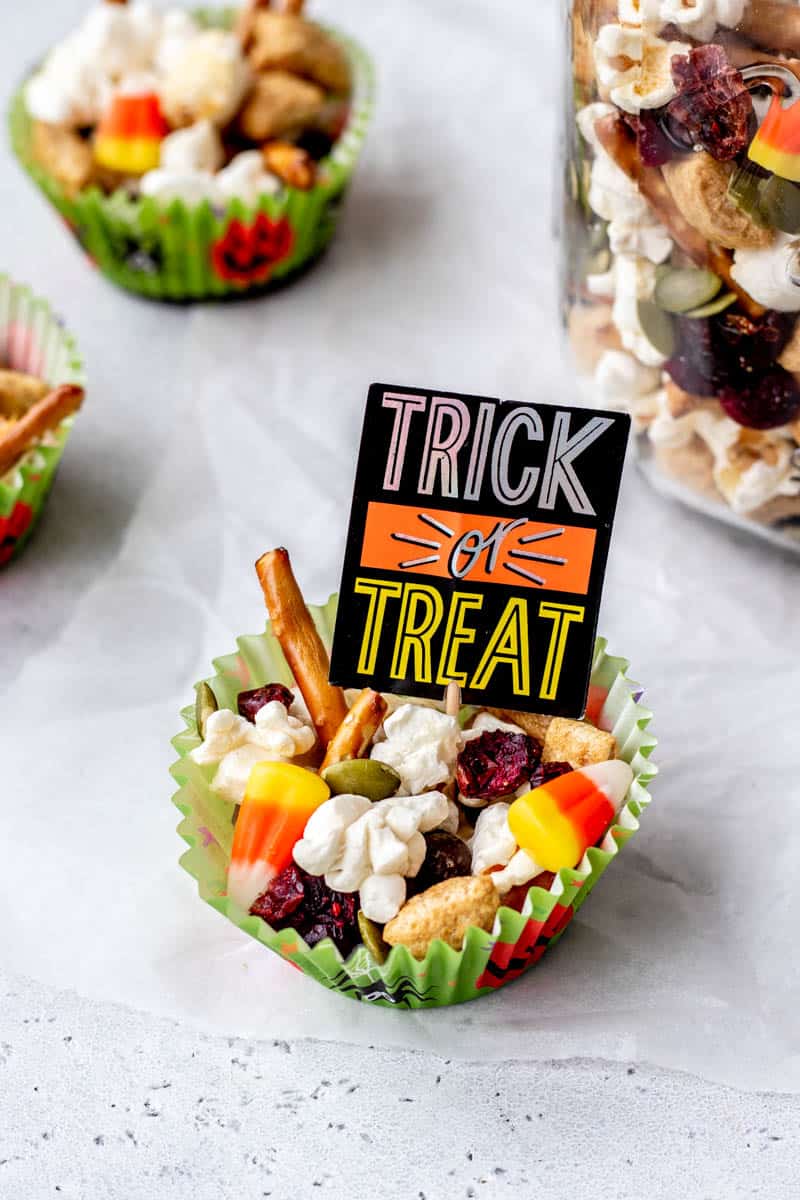 A muffin liner full of homemade Halloween trail mix with a trick or treat sign.