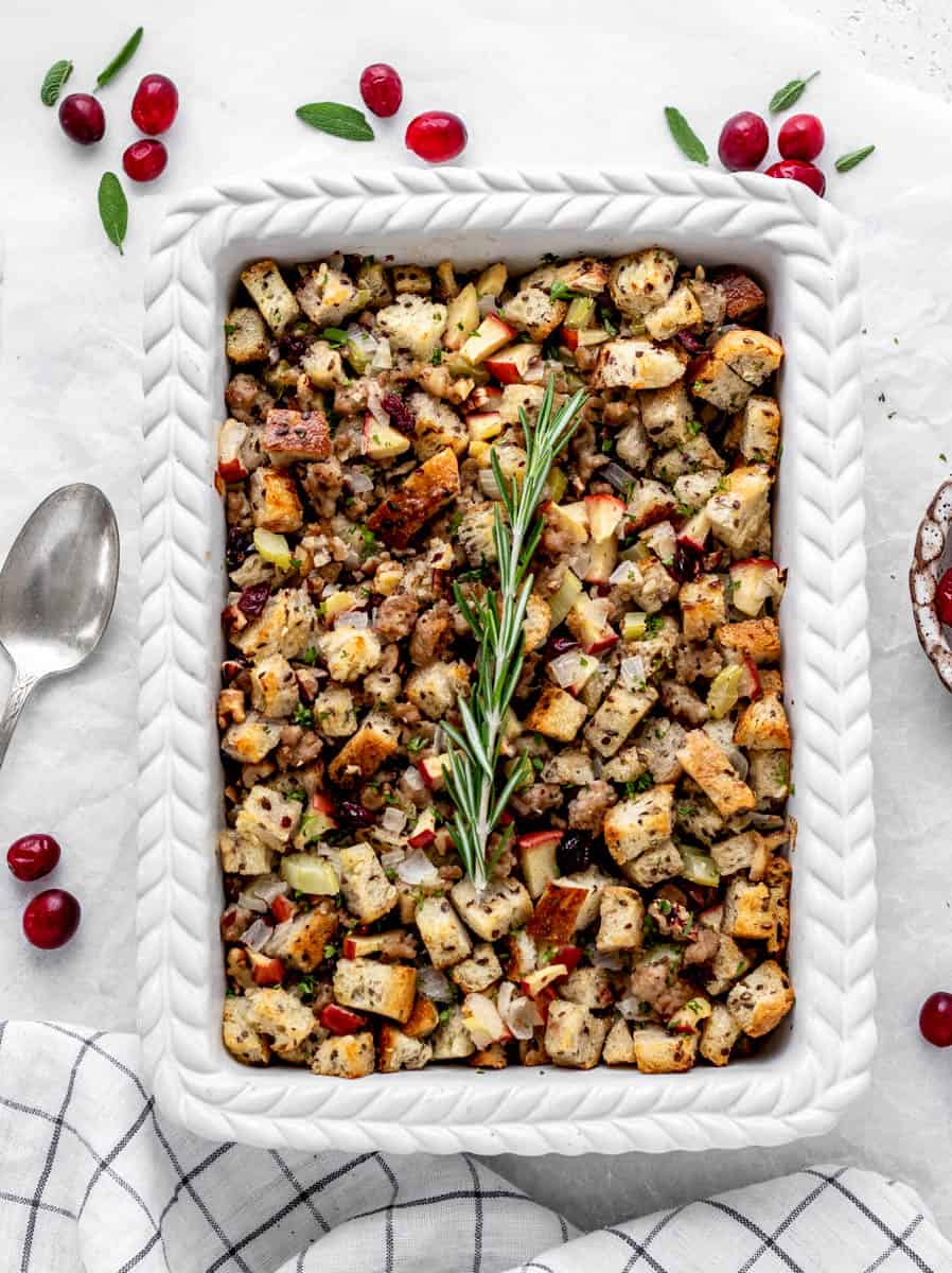 Baked Thanksgiving sausage stuffing in a casserole dish topped with fresh herbs.