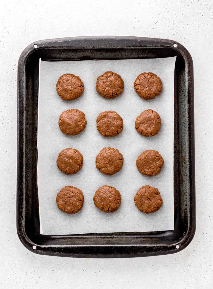 12 unbaked peanut butter blossom cookies, on a parchment lined baking sheet.
