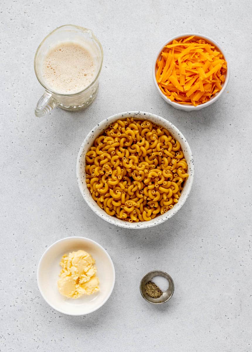 The ingredients needed for 5 ingredient mac and cheese, including evaporated milk, shredded sharp cheddar cheese, elbow macaroni, butter and salt and pepper.
