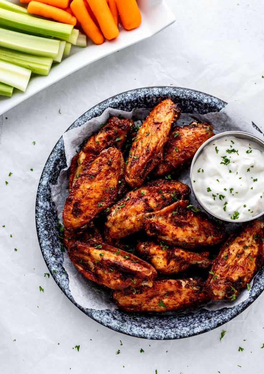 A plate of healthy air fryer baking powder chicken wings with a small bowl of dip on the side.