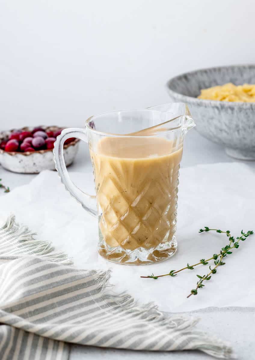 A glass pitcher of turkey gravy without drippings.