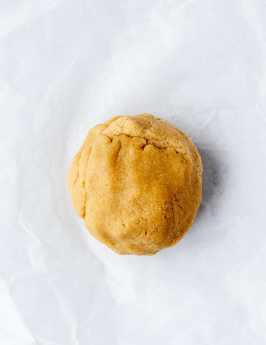 A ball of dough for almond flour cookies, on parchment paper.