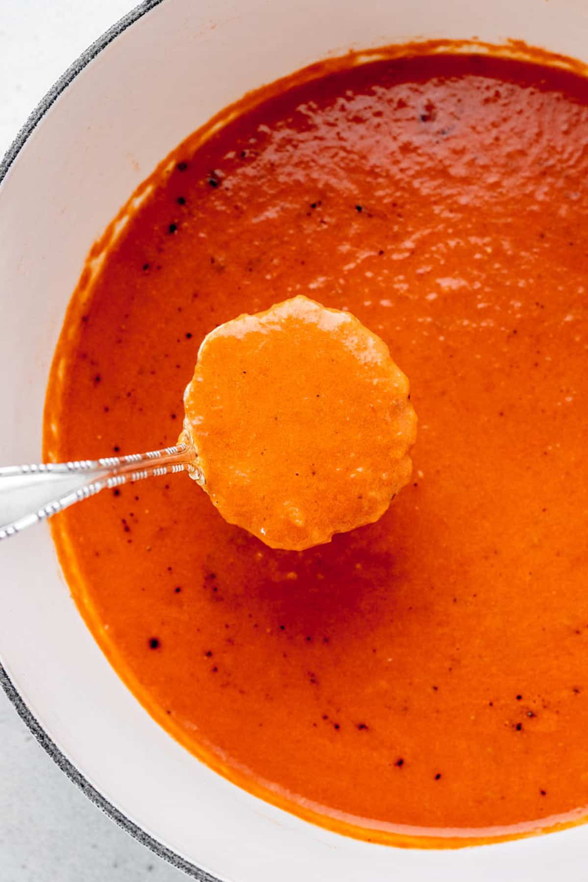 A ladle scooping out a serving of healthy tomato soup.