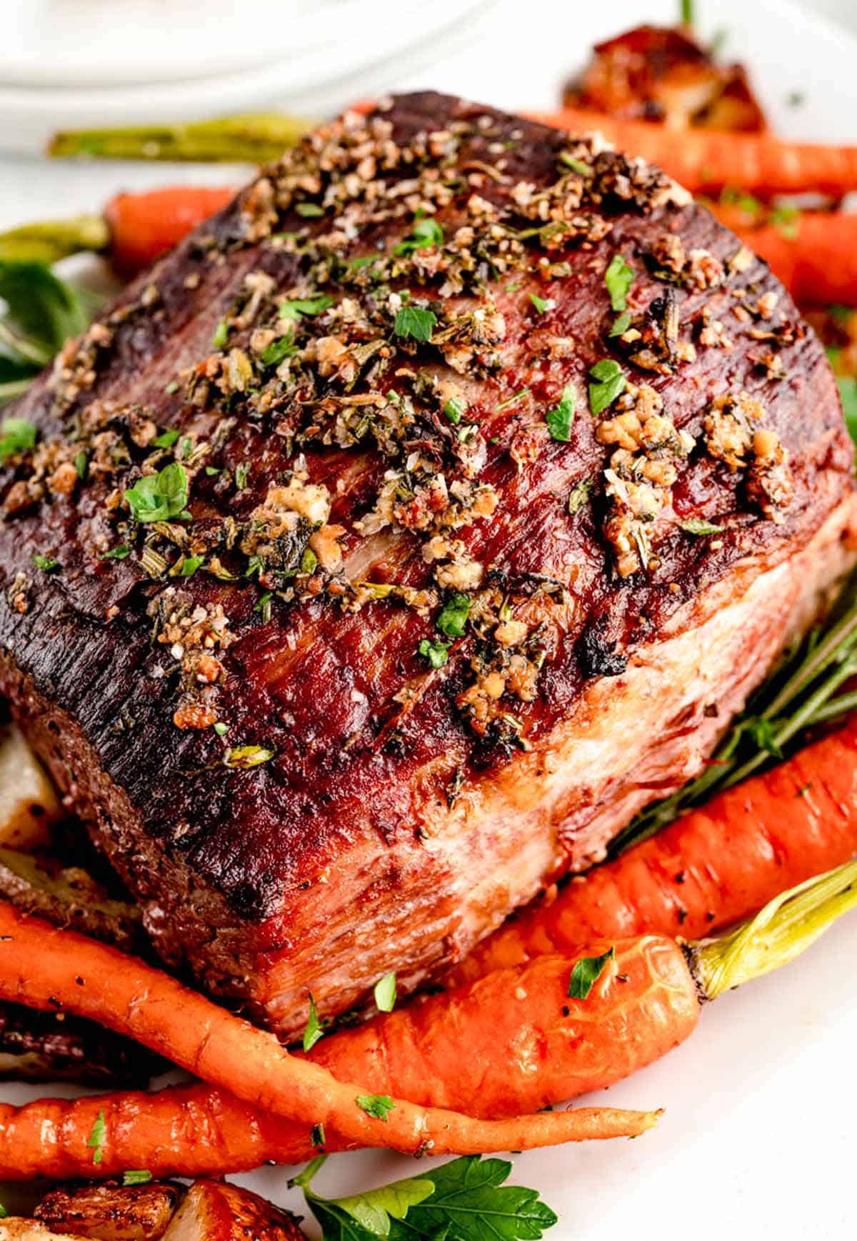 A whole roasted and uncarved Christmas roast beef with carrots.