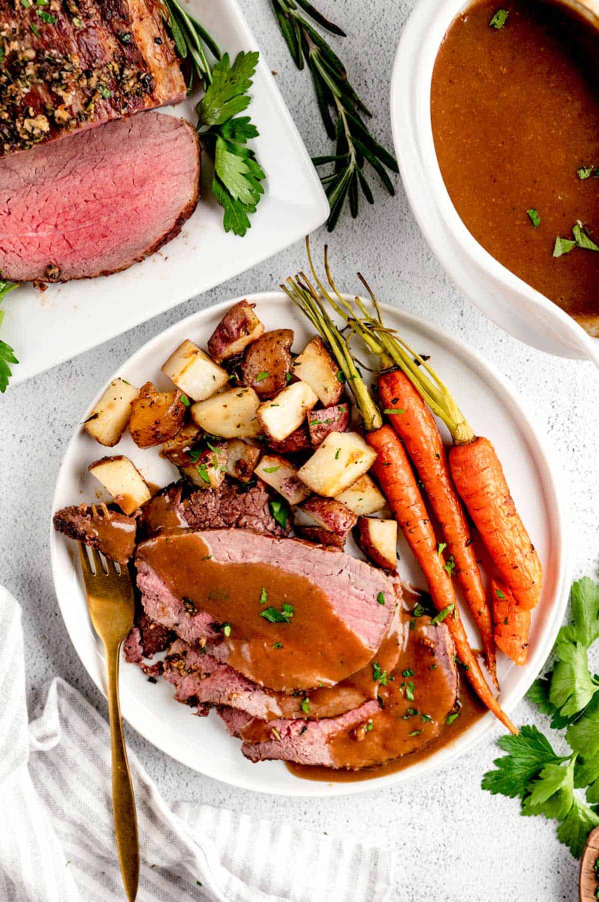 A plate showing a serving of Christmas roast beef with gravy, potatoes and carrots.