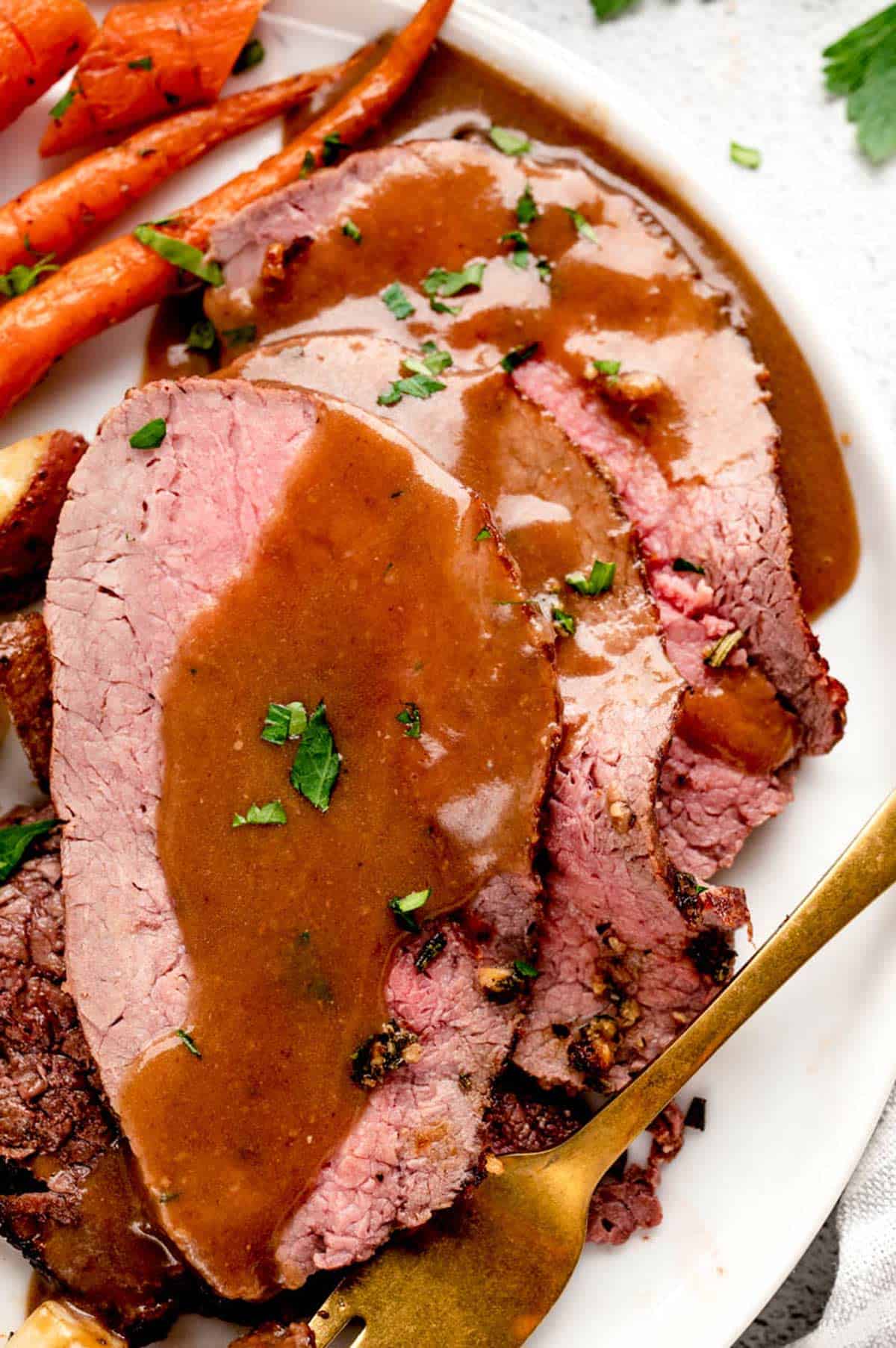 A serving of Christmas beef roast, with gravy and carrots.