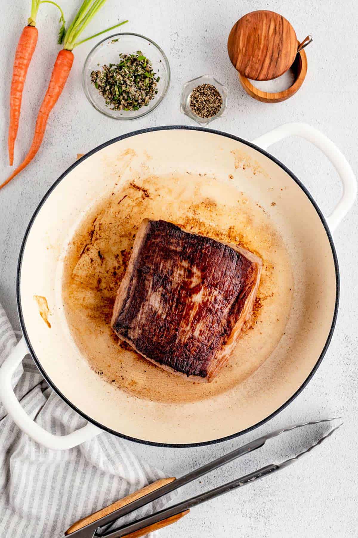 The eye of round roast after being seared on all sides, it is ready for the herb rub and vegetables.