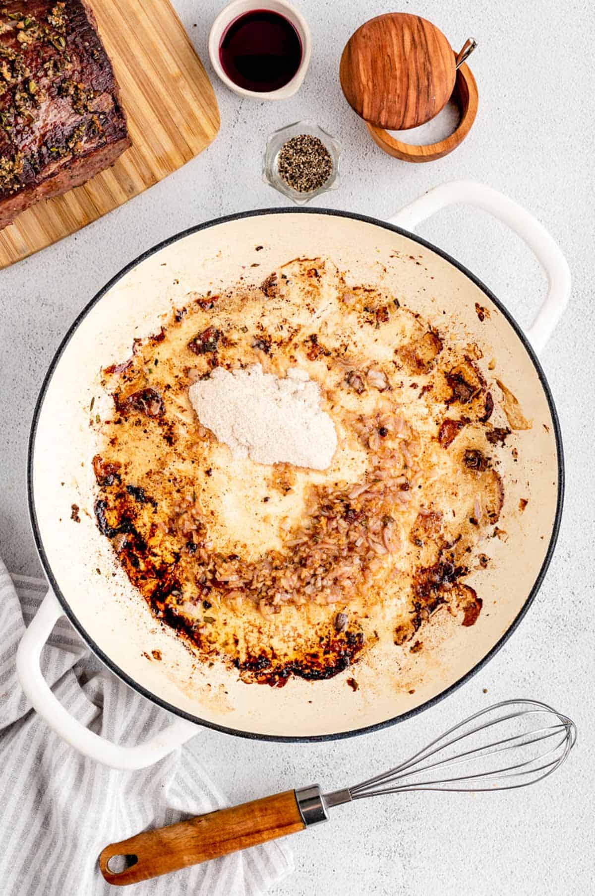 A pot with shallots and garlic cooking in the beef drippings of the holiday roast beef for the homemade gravy.