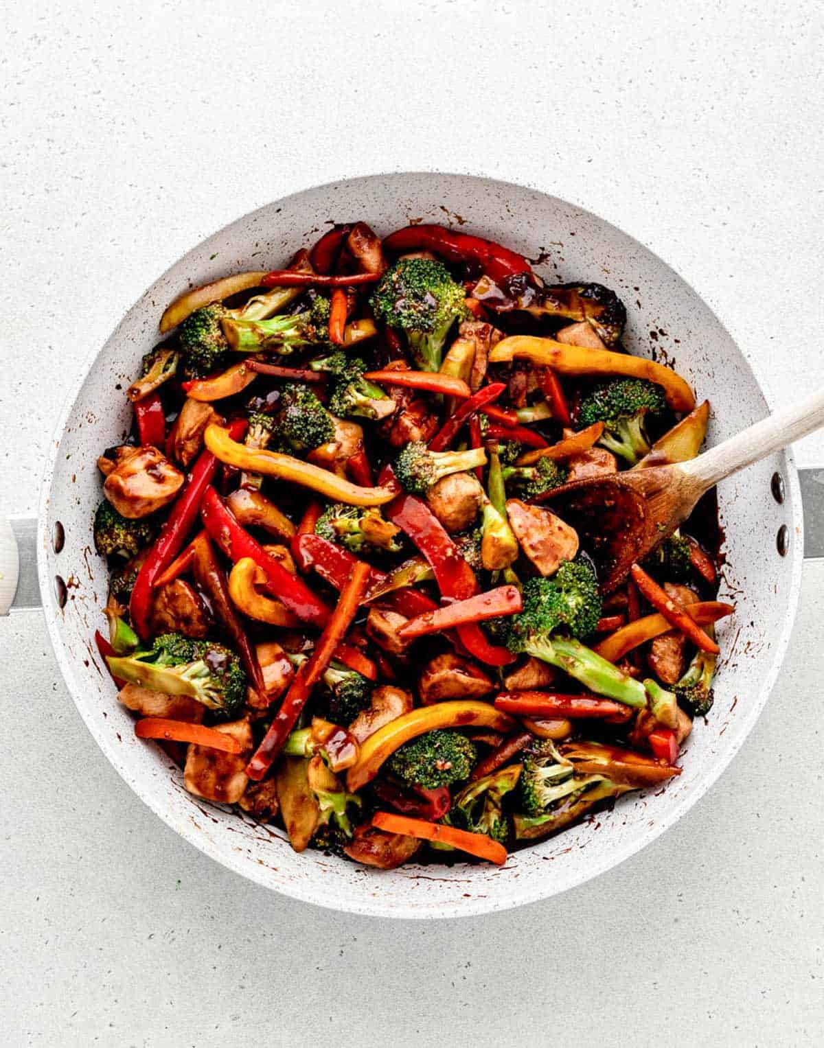 A pan of healthy stir fry with chicken, cooking in the stir fry sauce.