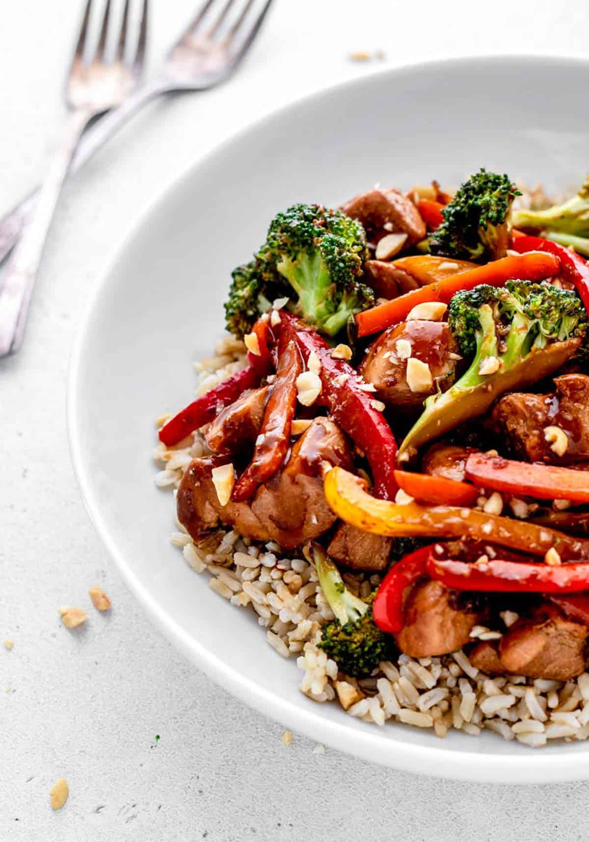 Healthy chicken stir fry served over rice with a garnish of peanuts.