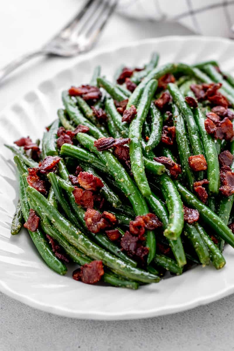 Green beans and bacon on a white serving plate.