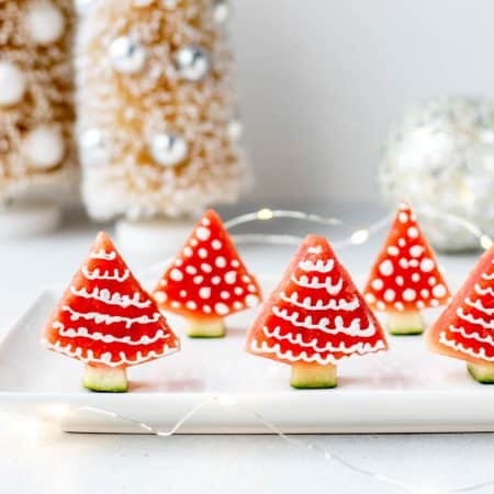 Christmas watermelon trees upright on a white plate.