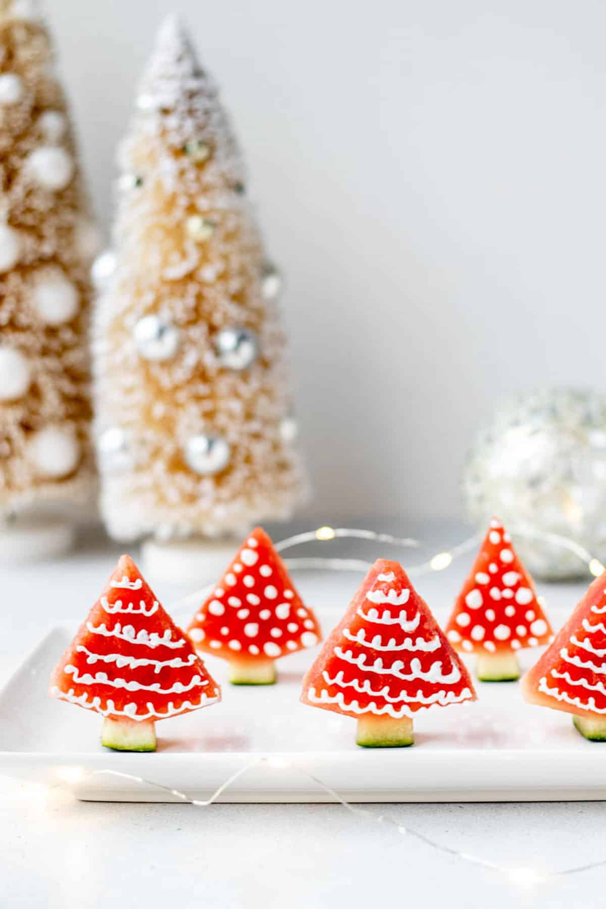 Christmas watermelon trees upright on a white plate.