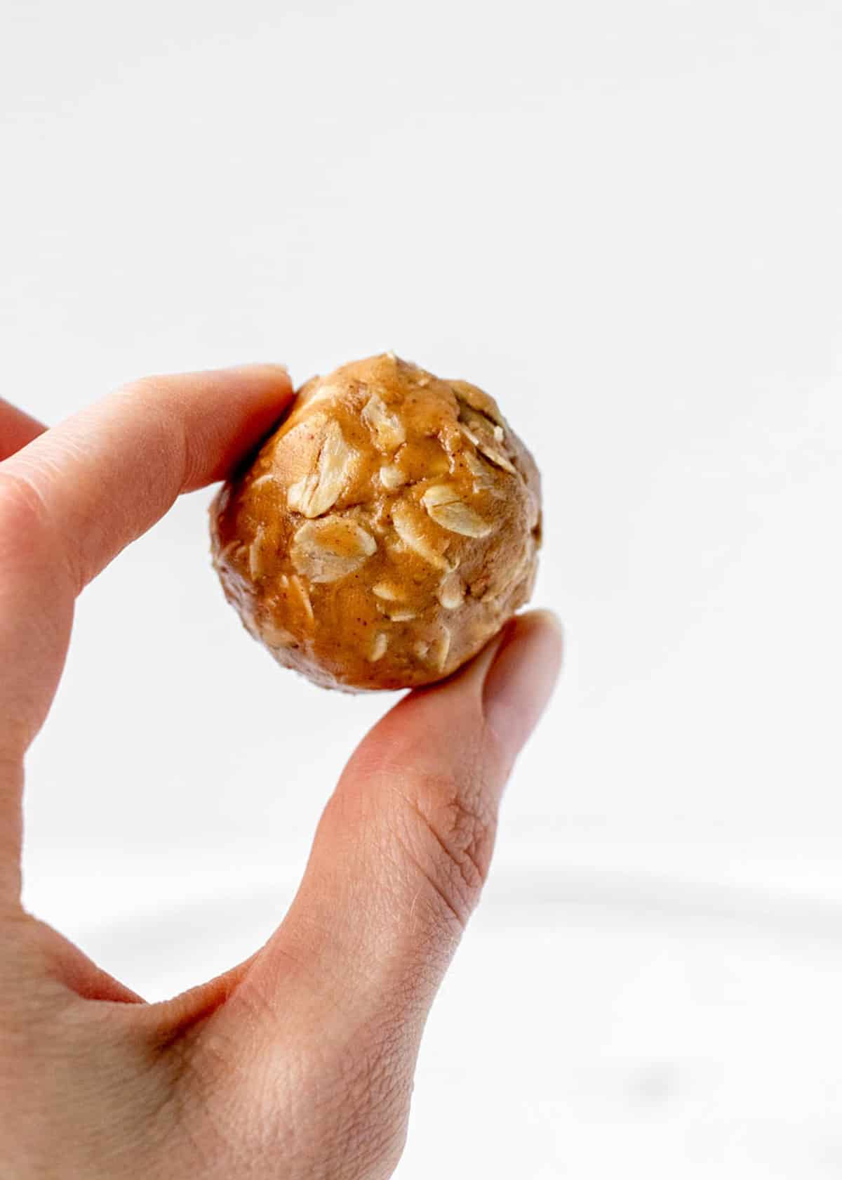 A hand holding up one of the peanut butter honey oatmeal balls.