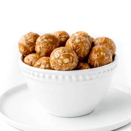 3-ingredient peanut butter oatmeal balls in a white bowl on a plate.