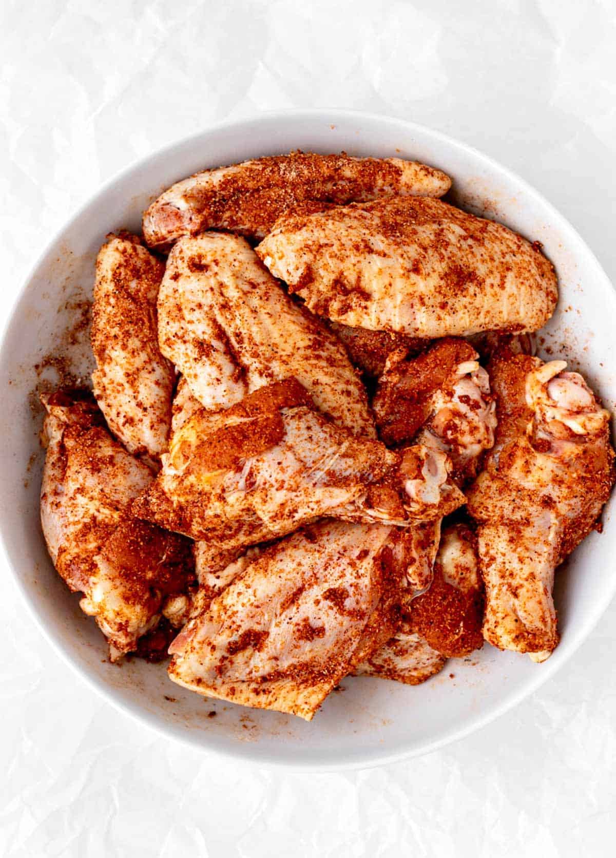A bowl of chicken wings with the dry rub seasoning on them.