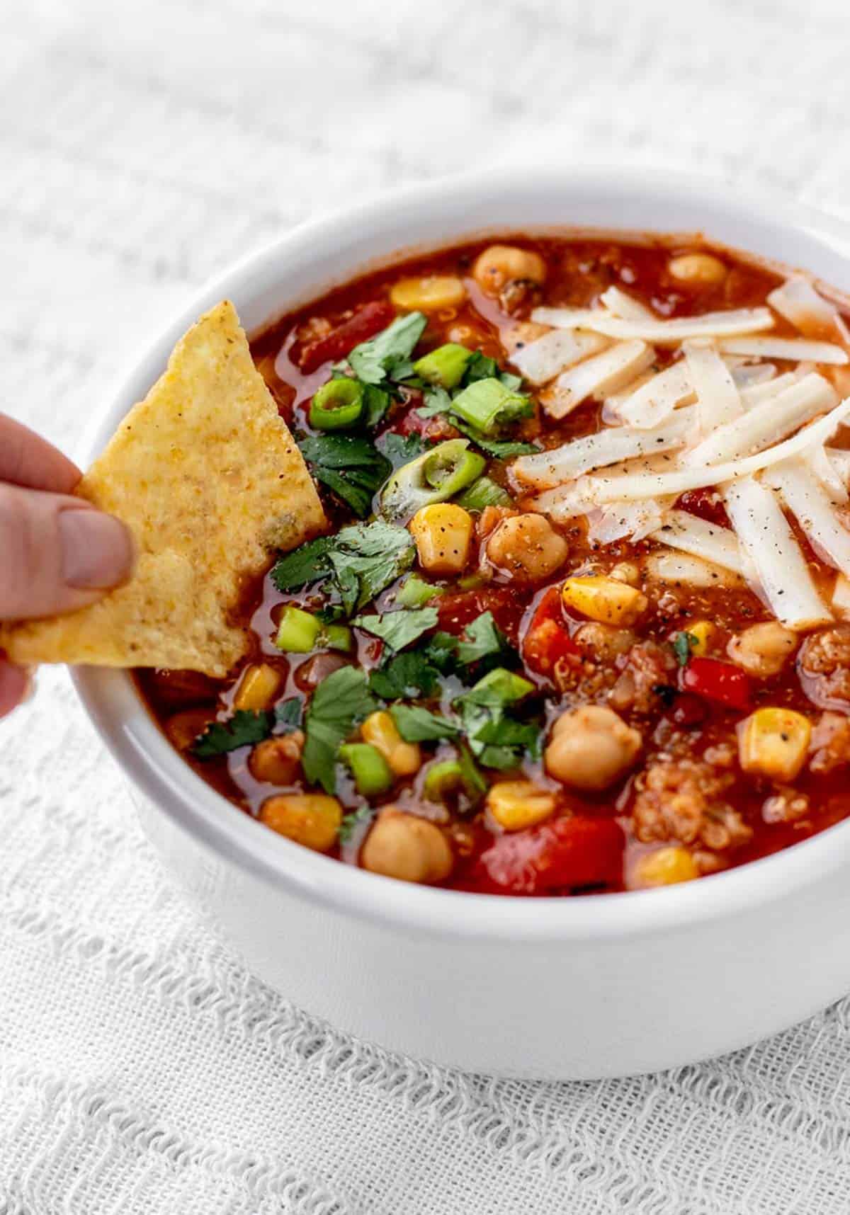A tortilla chip dipping into Mexican soup with garbanzo beans.
