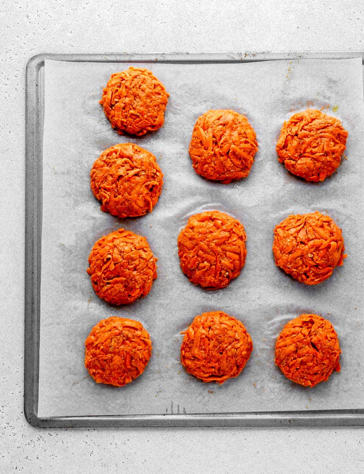 Sweet potato fritters on a baking sheet ready to be baked.