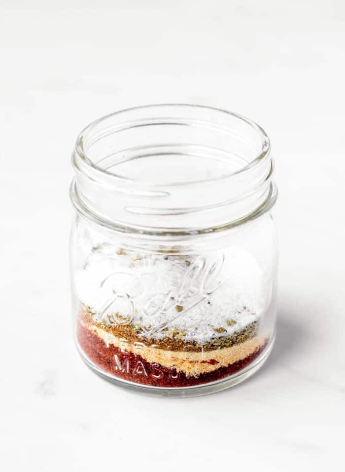 A small mason jar with spices for fajita seasoning measured out into it.