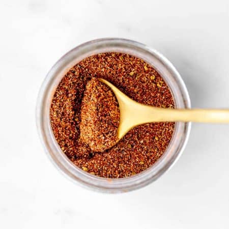A jar of authentic fajita seasoning with a spoon digging into it.