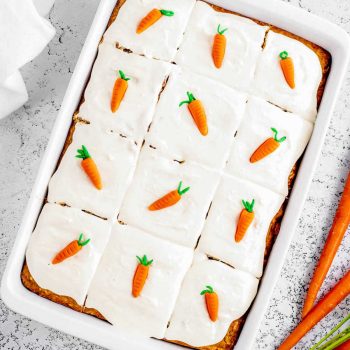 Overhead image of sliced carrot cake with cute carrot toppers in baking pan.