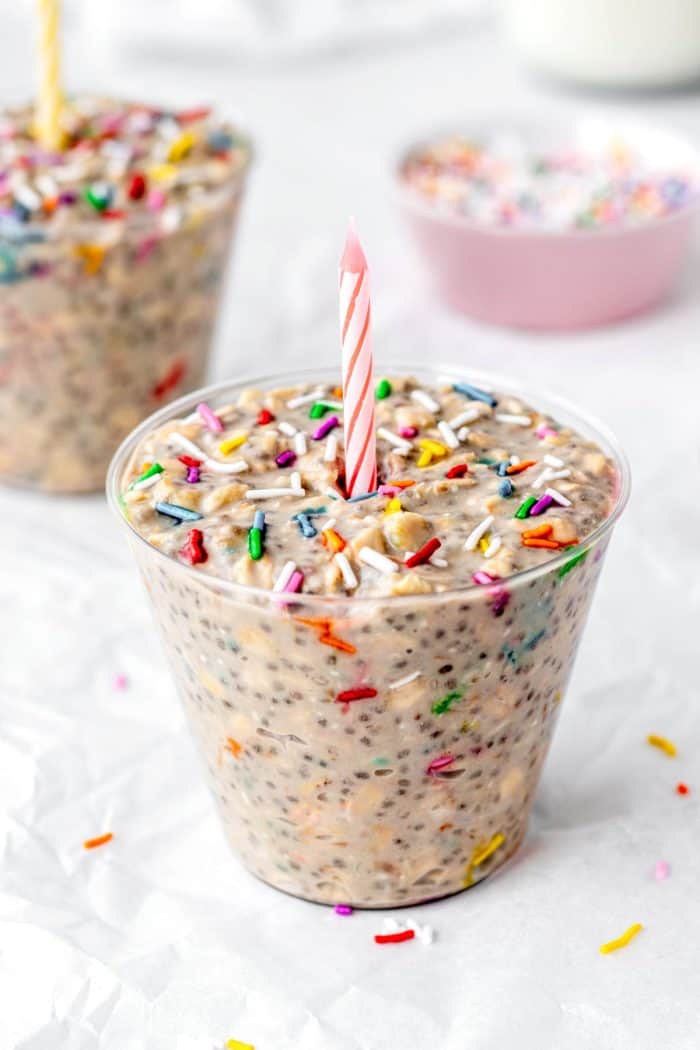Up close image of birthday cake overnight oats with a candle poked into the top.