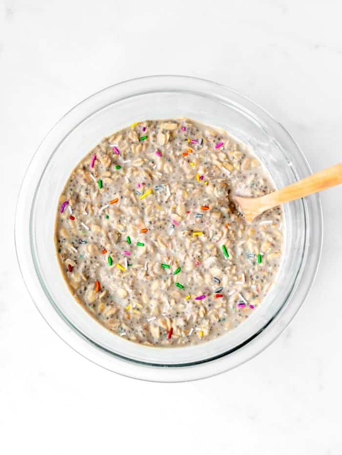 The thickened cake batter overnight oats mixture in a bowl with a wooden spoon.