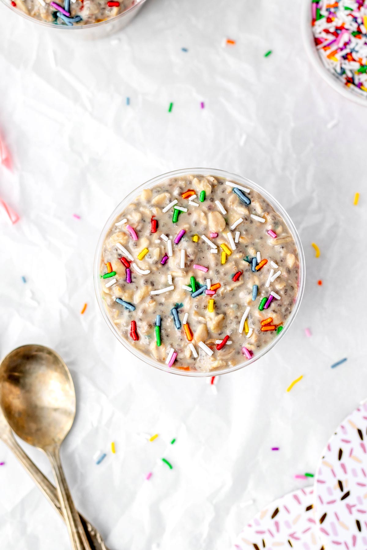 Overhead shot of birthday cake overnight oats in a cup topped with sprinkles.