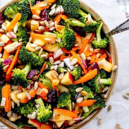 A bowl of broccoli apple salad with a fork digging into it.
