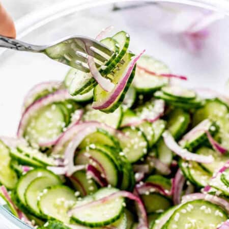 A fork lifting up some of the Asian cucumber salad with rice vinegar and sesame oil dressing.