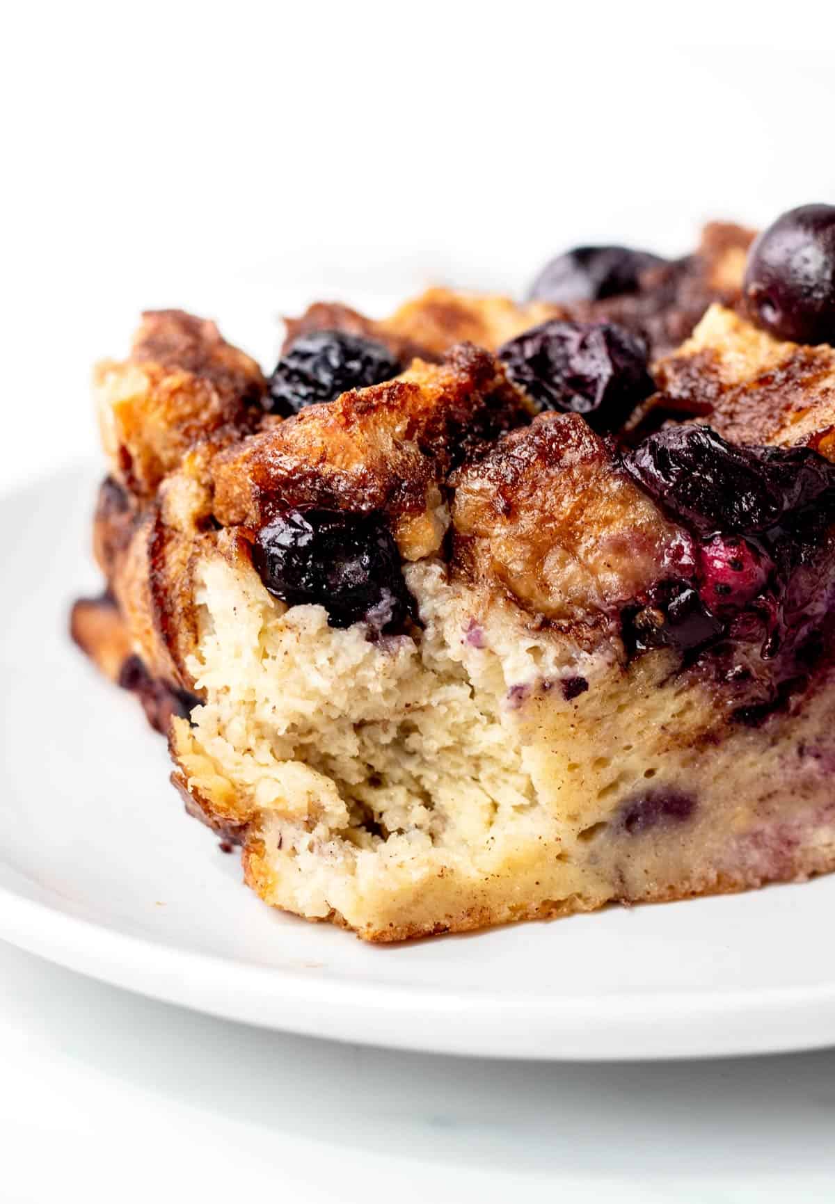 A close up of the inside texture of a piece of blueberry French toast casserole on a plate.