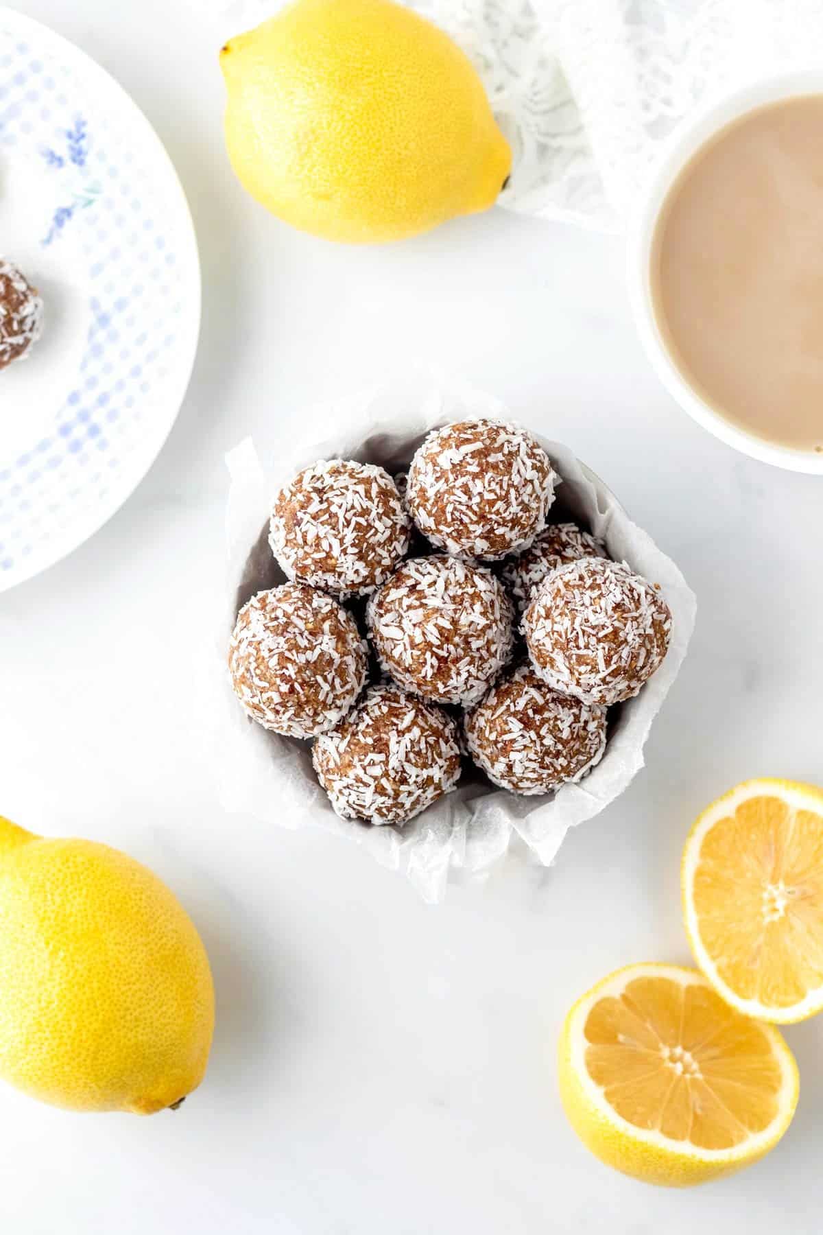An overhead image of lemon balls in a small white bowl next to lemons.