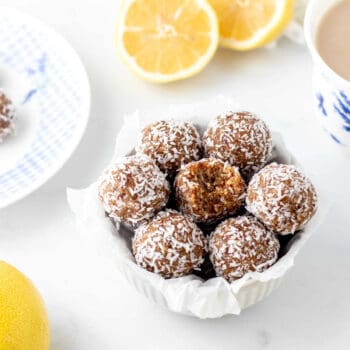 A bowl of no bake coconut lemon balls with a bite taken out of the middle energy ball.