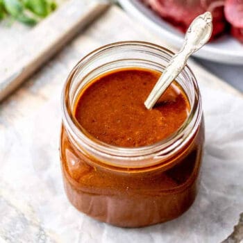A jar of healthy steak marinade with a spoon in it.