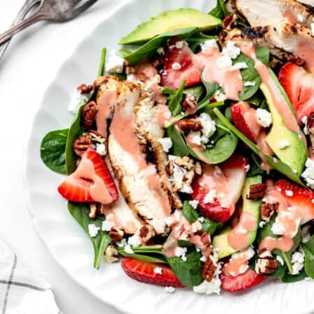 Up close image of grilled chicken and strawberry salad on a white plate.