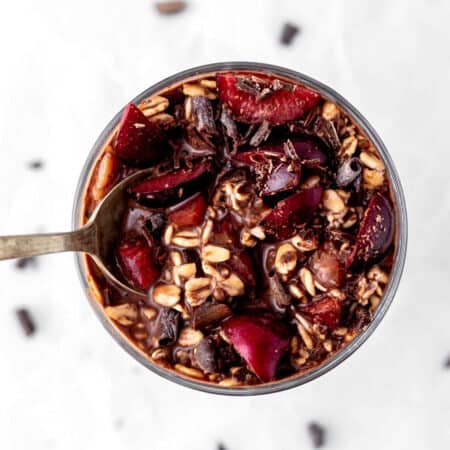 Overhead image of chocolate cherry overnight oats in a glass with a spoon digging in.