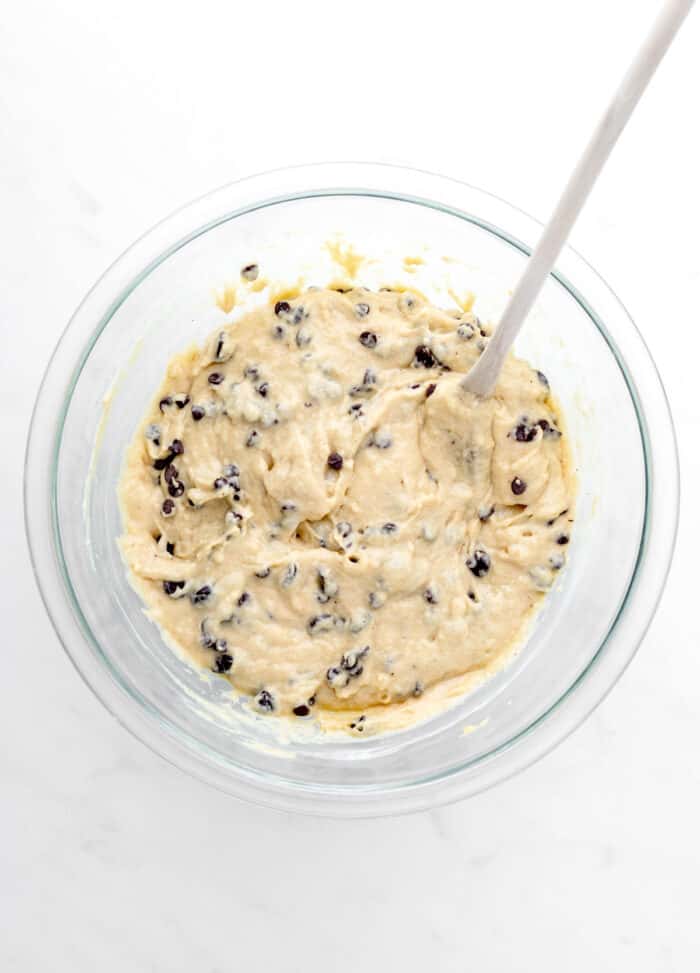 Chocolate chips added to the muffin batter in a large bowl.