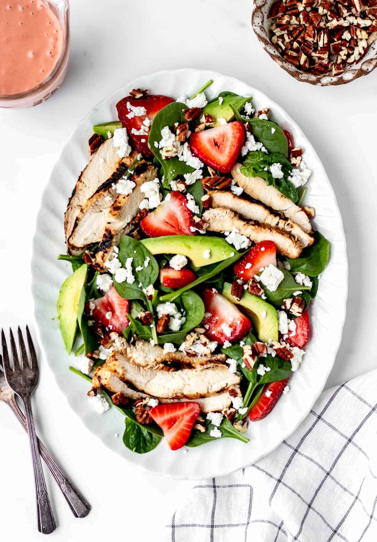 Grilled chicken spinach strawberry salad on a plate.