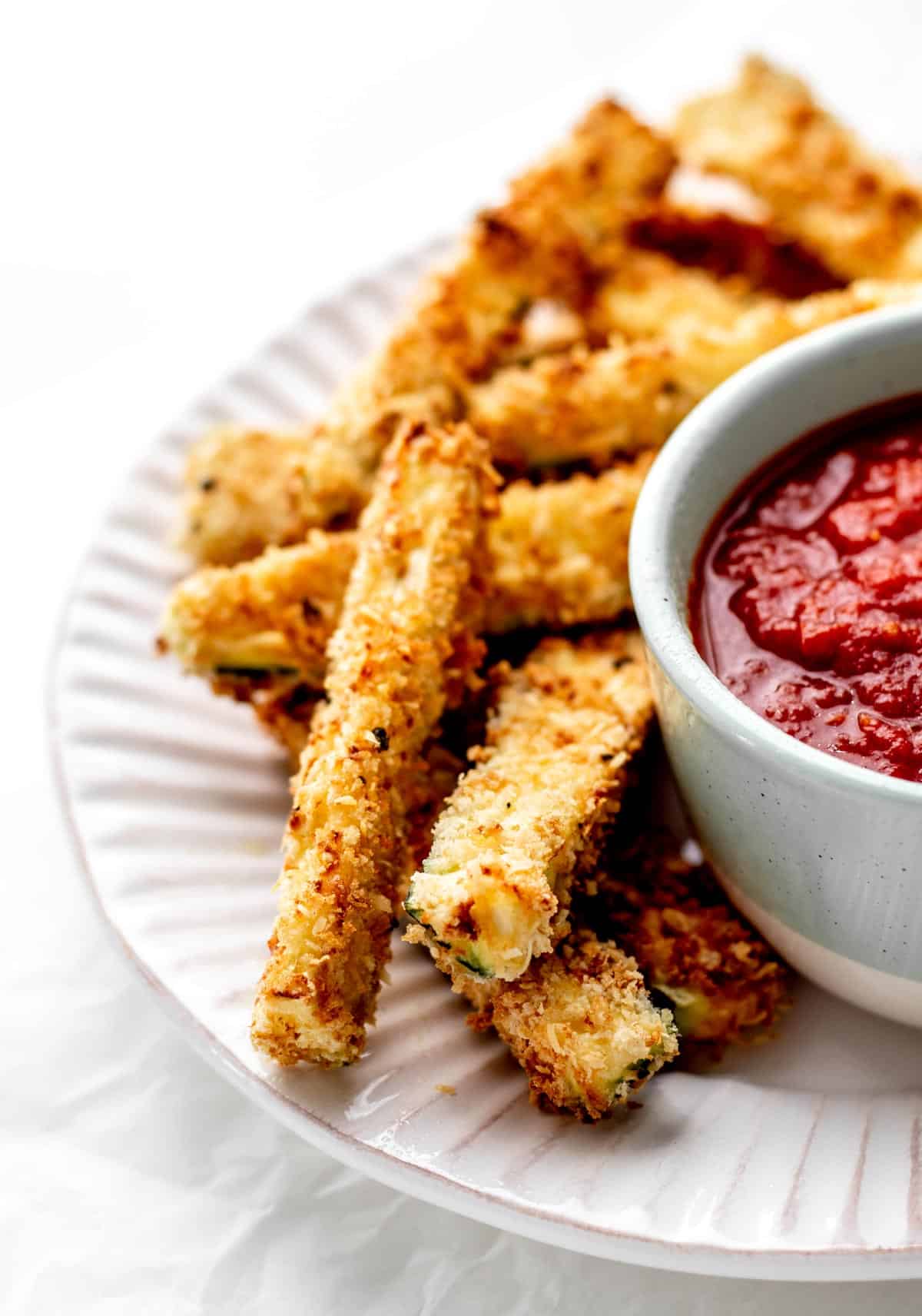 A close up image of a the crispy air fryer zucchini fries on a plate.