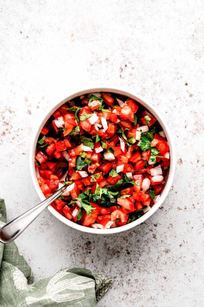 Homemade pico de gallo being mixed together in a bowl.