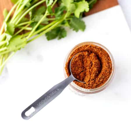 Homemade healthy taco seasoning in a small mason jar with a spoon.